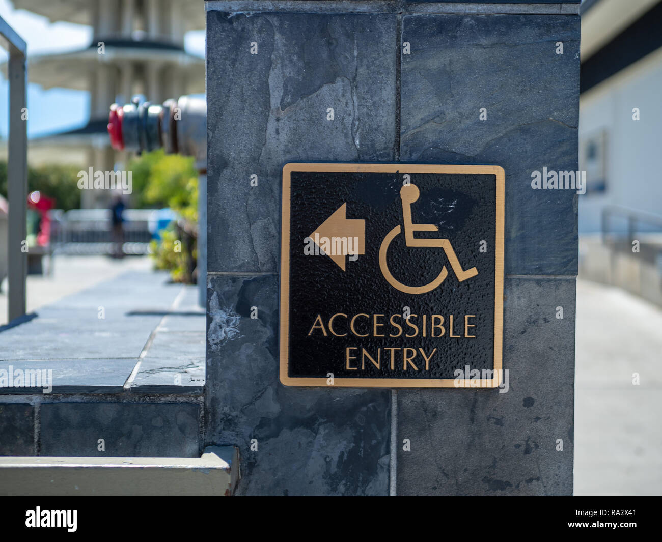 Oro e nero accessibile entrata segno distacco con sedia a rotelle il logo di handicap con la freccia rivolta verso sinistra Foto Stock