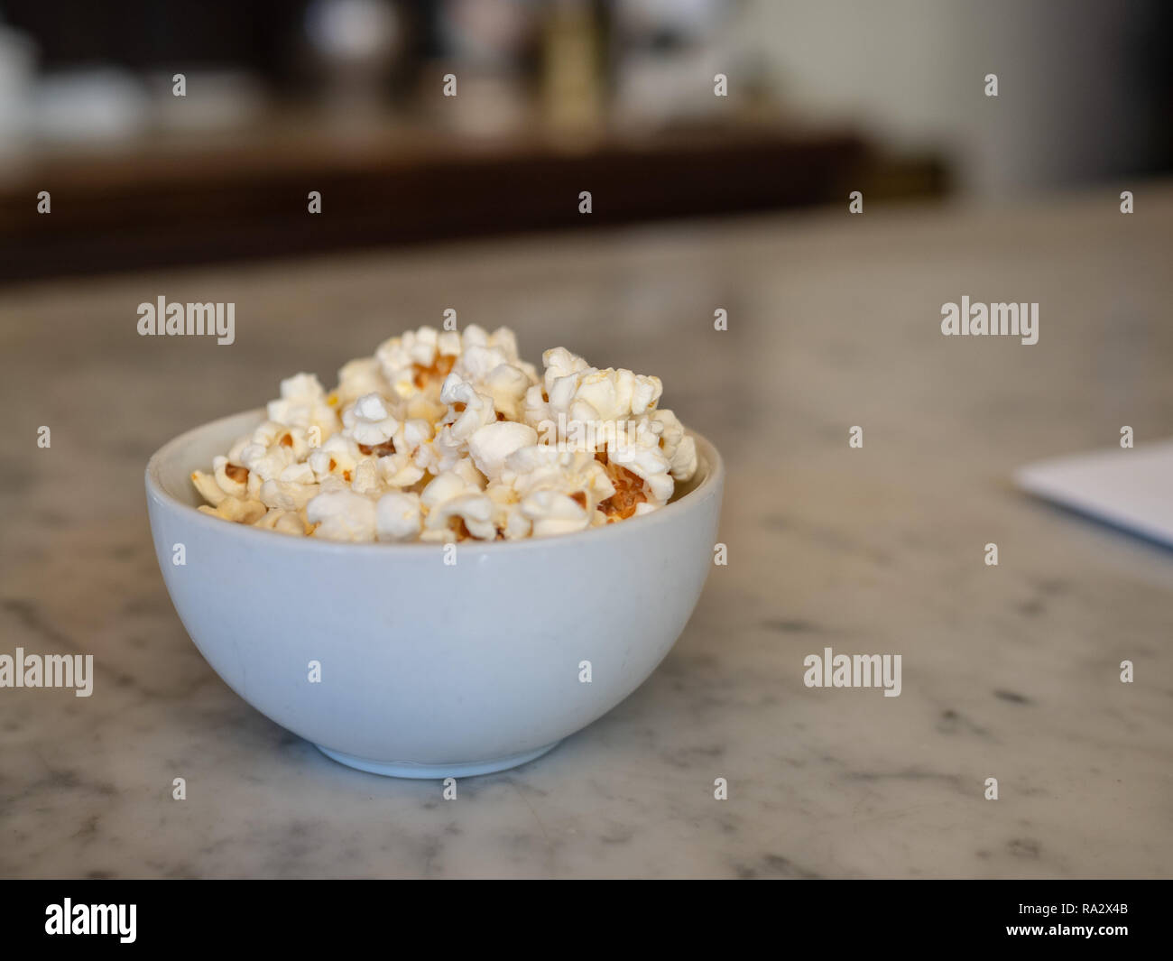 Una piccola ciotola di popcorn fresco seduto sul bancone di marmo con menu Foto Stock