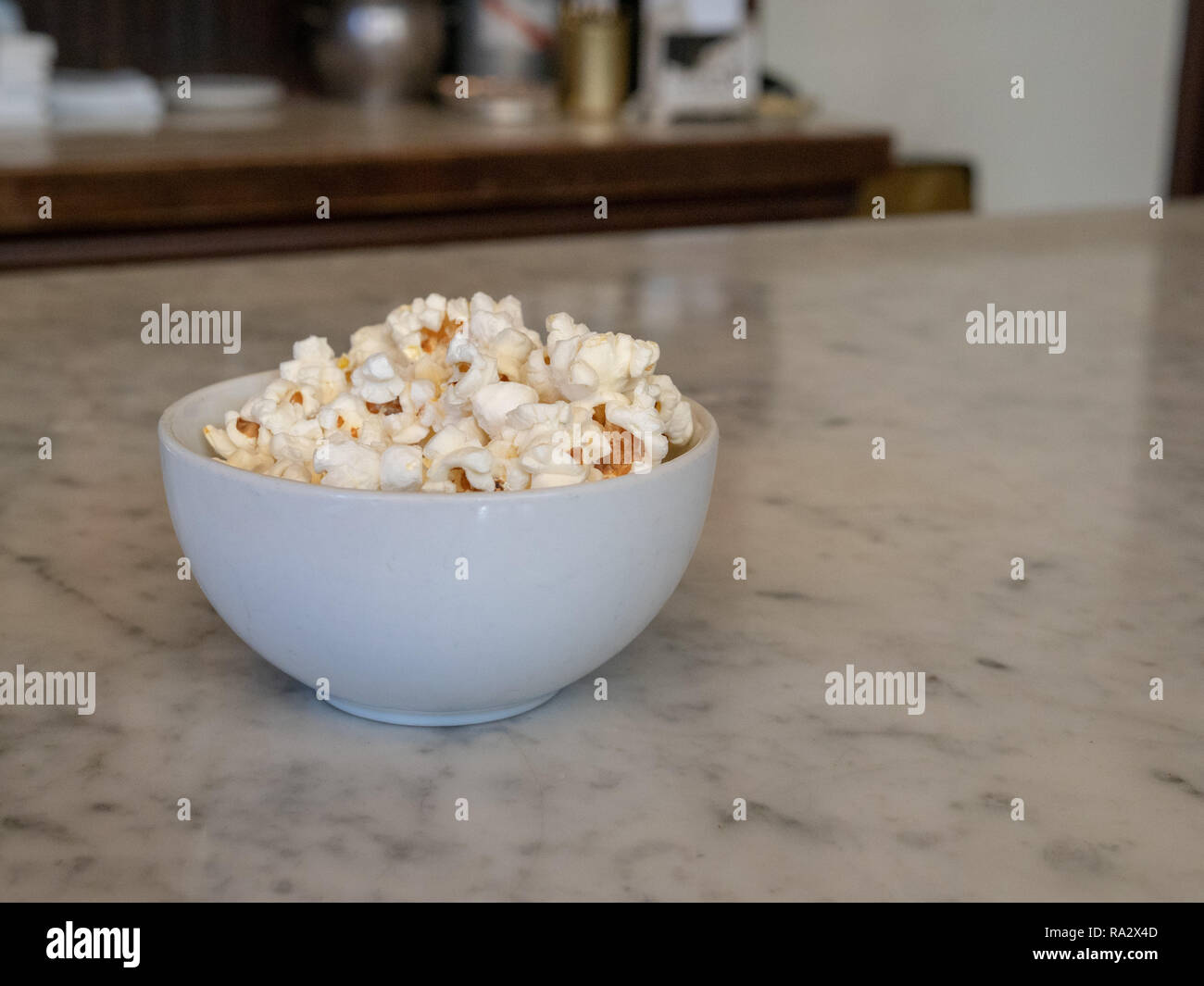 Piccolo mucchio di popcorn fresco nel vaso di porcellana seduto su un bancone di marmo Foto Stock