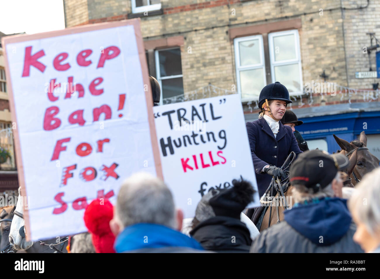 Uttoxeter, Staffordshire, Regno Unito. Il 1 di gennaio 2019. Il Meynell & South Staffordshire Hunt raccogliere in Uttoxeter centro città per il 2019 Nuovi anni giorno caccia. Circa 25 piloti e i loro cani in giro per la città e sono soddisfatti da 30 manifestanti con cartelli, alcuni dei quali indossare maschere di Fox. 200 sostenitori di suoneria allegria come la caccia arriva mentre i contestatori sentire la loro voce con forte boo. Credito: Richard Grange/Alamy Live News Foto Stock