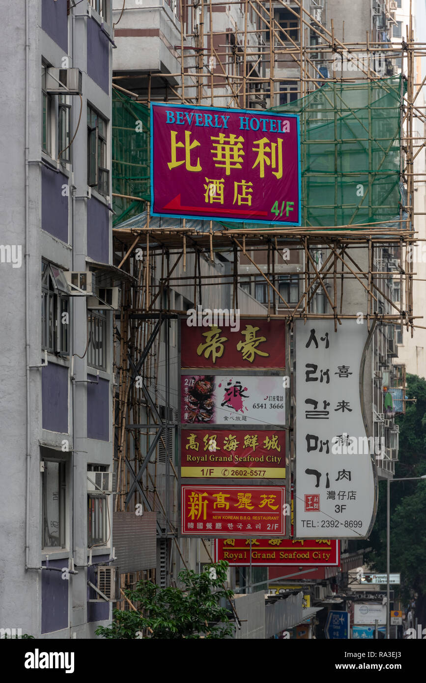 I pannelli pubblicitari e ponteggi di bambù competere per lo spazio per gli edifici di Lockhart Road a Hong Kong di Wan Chai district Foto Stock