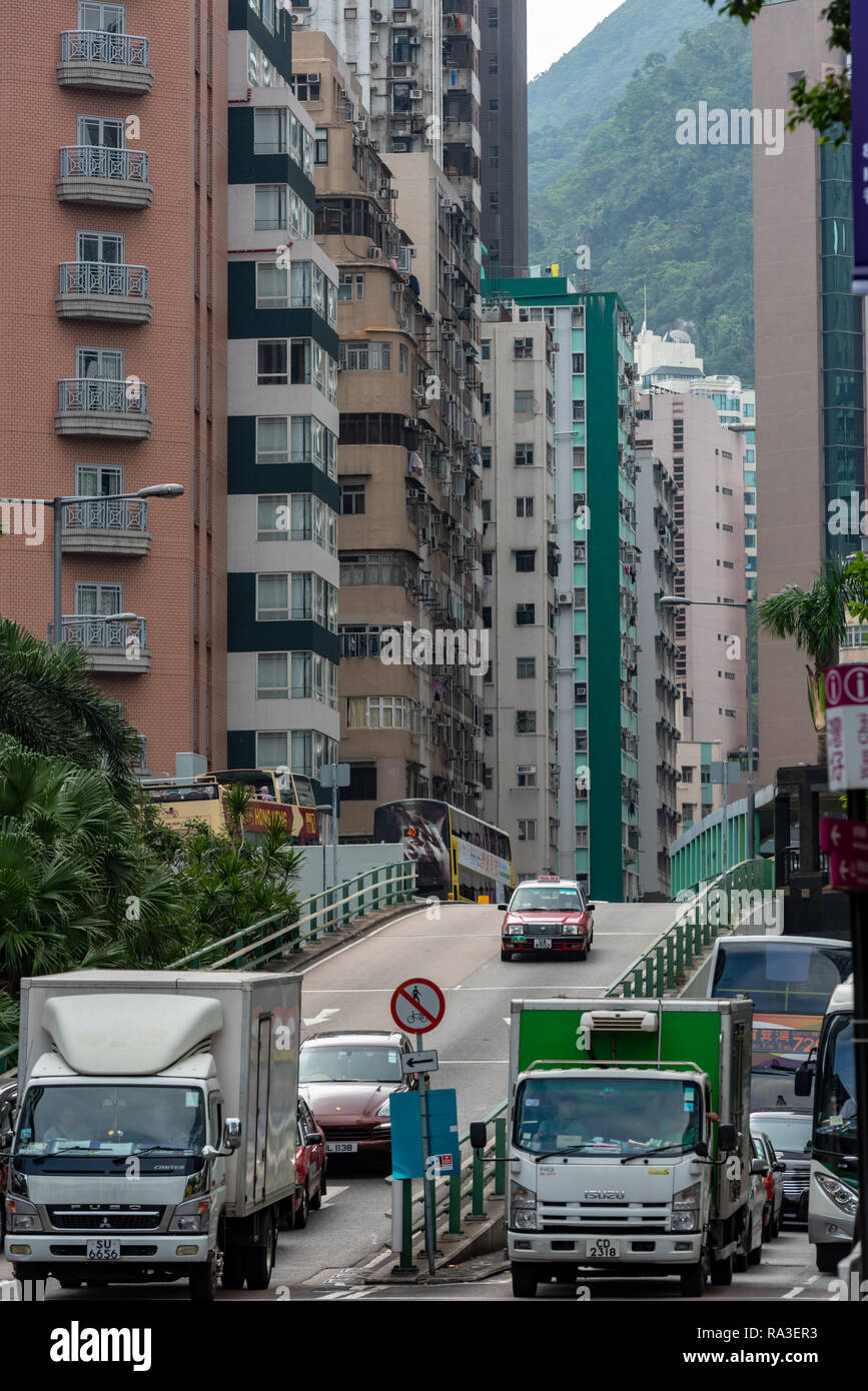 Il traffico si ritaglia la sua strada tra Wan Chai torre di blocchi lungo Fleming Road, con lo sfondo del monte Cameron Foto Stock