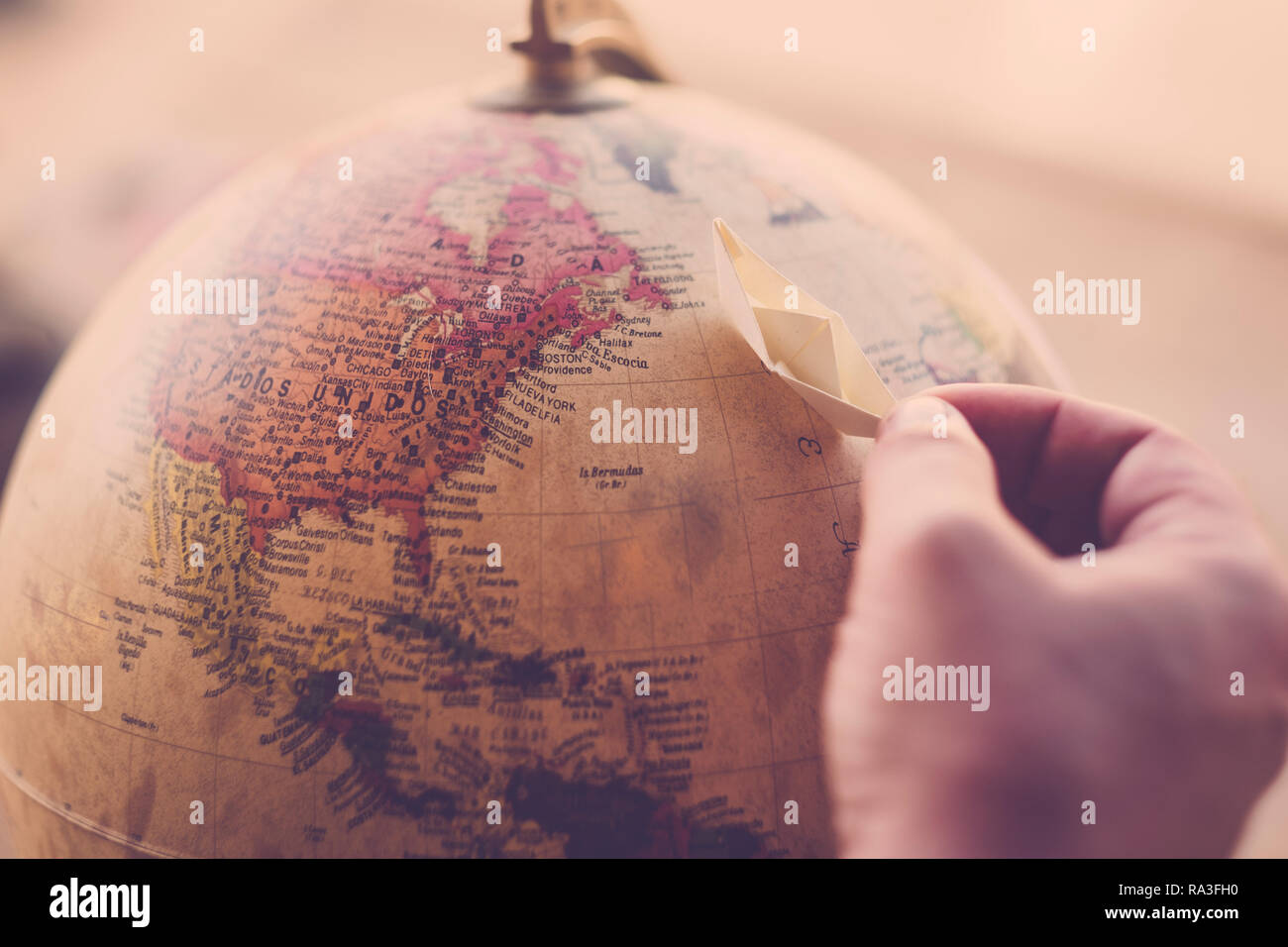 Il pianeta terra sulla sfera con la mano e la piccola barca di carta per i viaggi e il concetto di sogno - spostare in giro per il mondo con la nave di crociera e seguire i vostri wanderlus Foto Stock