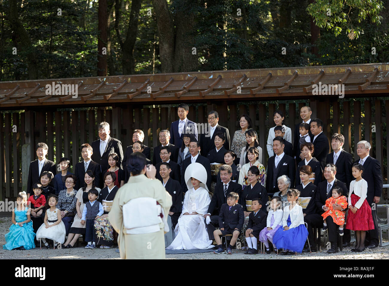 Lo Shintoismo corteo nuziale con la sposa indossa il tradizionale watabōshi cappa bianca che posano per una foto formale in Meiji Jingu sacrario scintoista Foto Stock