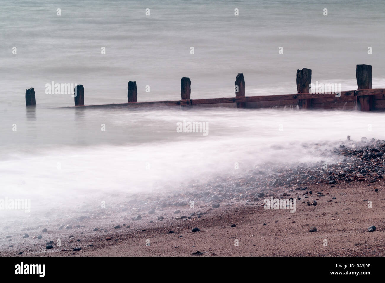 Worthing beach catturata mediante una lenta velocità di otturazione in modo tale che il mare sembra liscia. Foto Stock