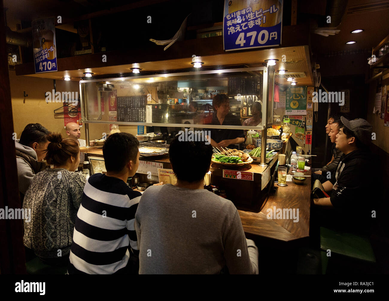 Un giapponese chef a caldo e fumoso Tokyo street restaurant, come la gente del posto per mangiare e per bere nella notte. Giappone Foto Stock