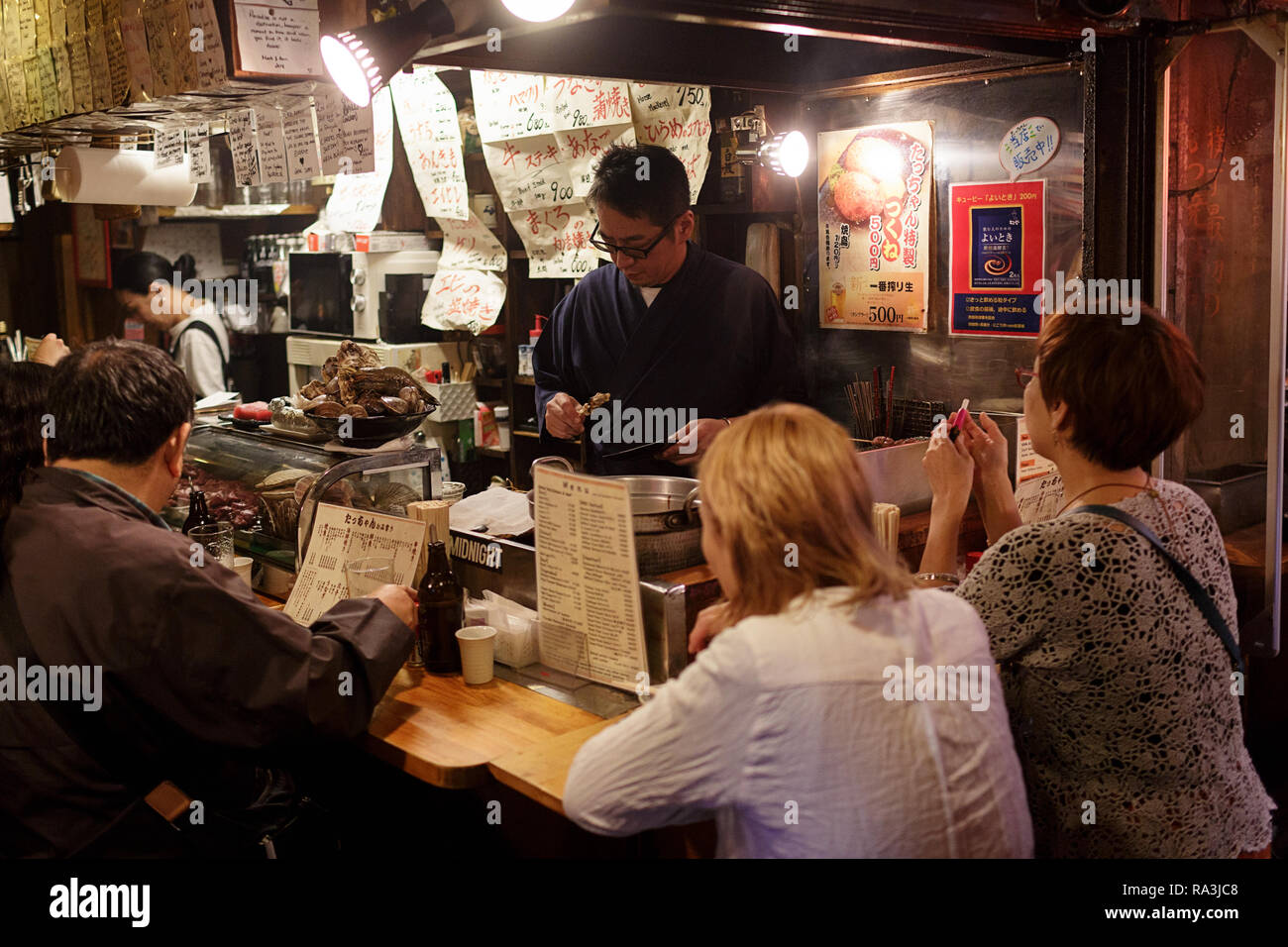 Un giapponese chef a caldo e fumoso Tokyo street restaurant, come la gente del posto per mangiare e per bere nella notte. Giappone Foto Stock