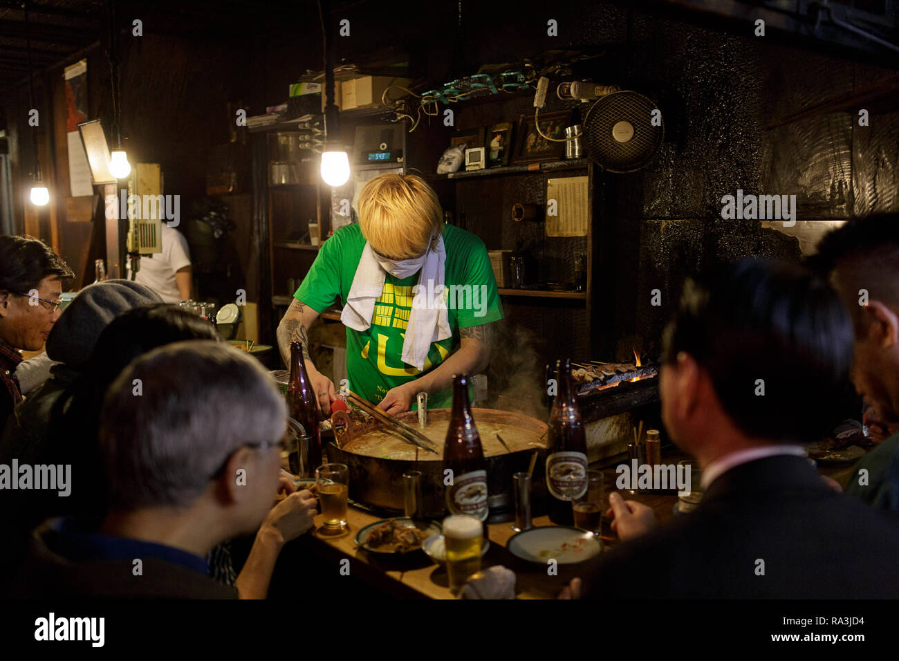 Un giapponese chef a caldo e fumoso Tokyo street restaurant, come la gente del posto per mangiare e per bere nella notte. Omoide Yokocho , Giappone Foto Stock