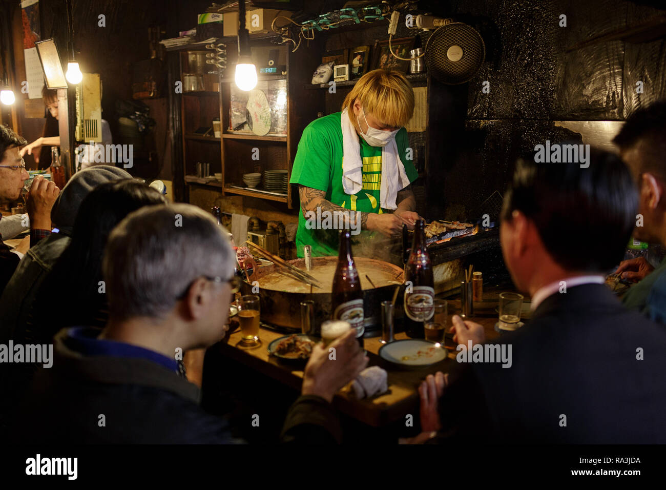 Un giapponese chef a caldo e fumoso Tokyo street restaurant, come la gente del posto per mangiare e per bere nella notte. Omoide Yokocho , Giappone Foto Stock