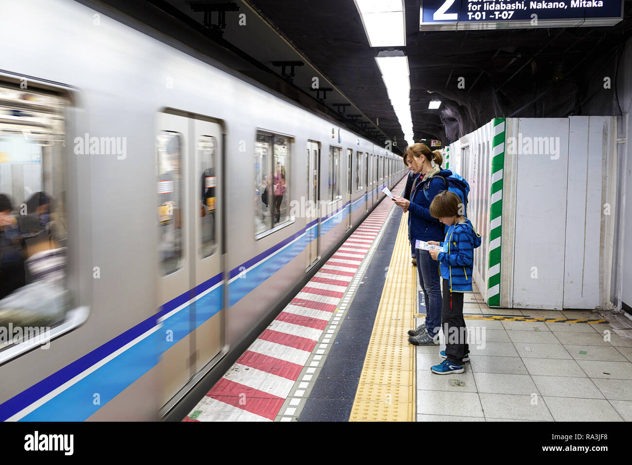 Western madre e figlio i viaggiatori in attesa in metropolitana per il passaggio di un treno, Tokyo Foto Stock