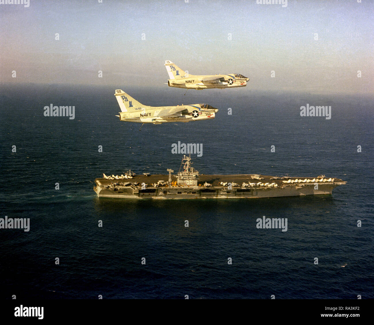 1979 - antenna di una vista di tribordo della centrale nucleare-powered portaerei USS NIMITZ (CVN-68) in corso con due A-7E Corsair II aeromobili da Light Attack Squadron 82 (VA-82) in volo sopra la nave. Foto Stock