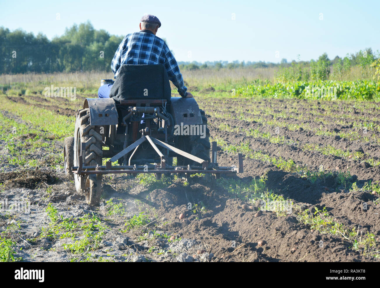 Imprenditore nel campo con il trattore. Coltivatore su vecchio trattore a mano aratura in campo. Foto Stock