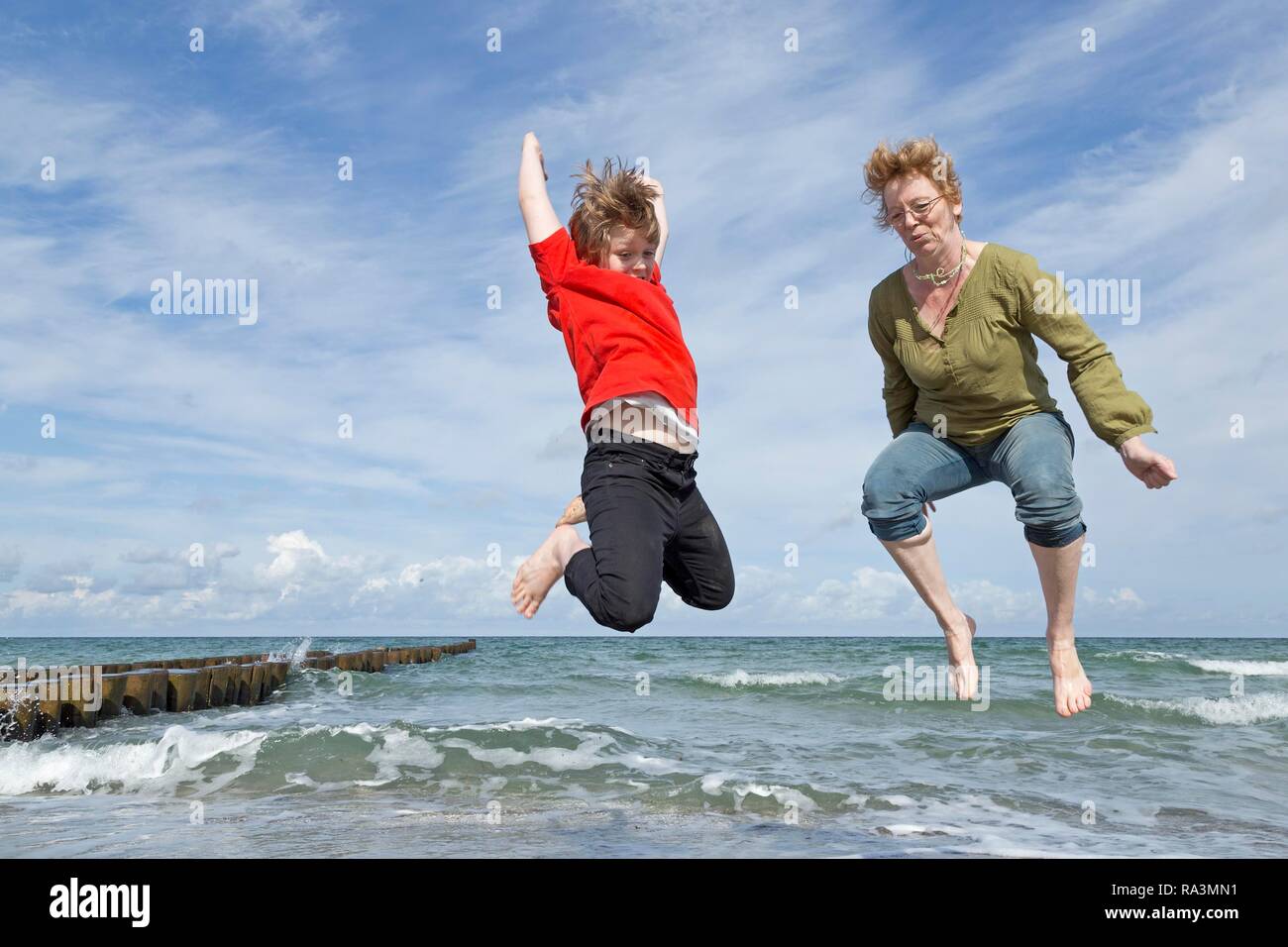 Madre e figlio salto sulla spiaggia, Ahrenshoop, Fischland, Meclemburgo-Pomerania, Germania Foto Stock