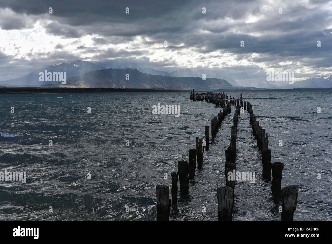 Raggi di sole rompere attraverso le nuvole scure, decadeva jetty, dietro Isla Diego Portales, Puerto Natales, provincia Última Esperanza, Cile Foto Stock