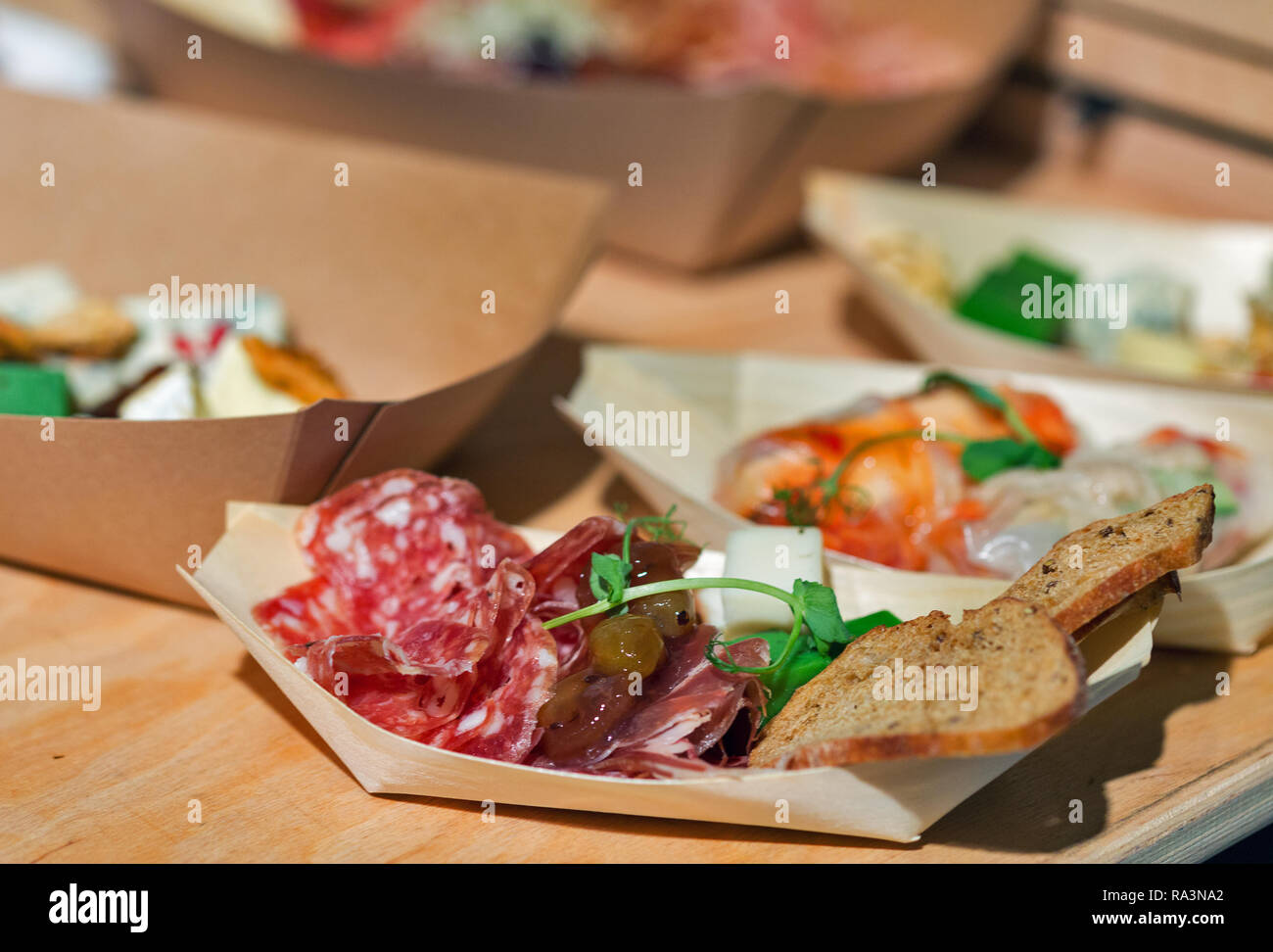 Varietà di spuntini con salame, prosciutto, rucola e pane in piastre di carta closeup Foto Stock