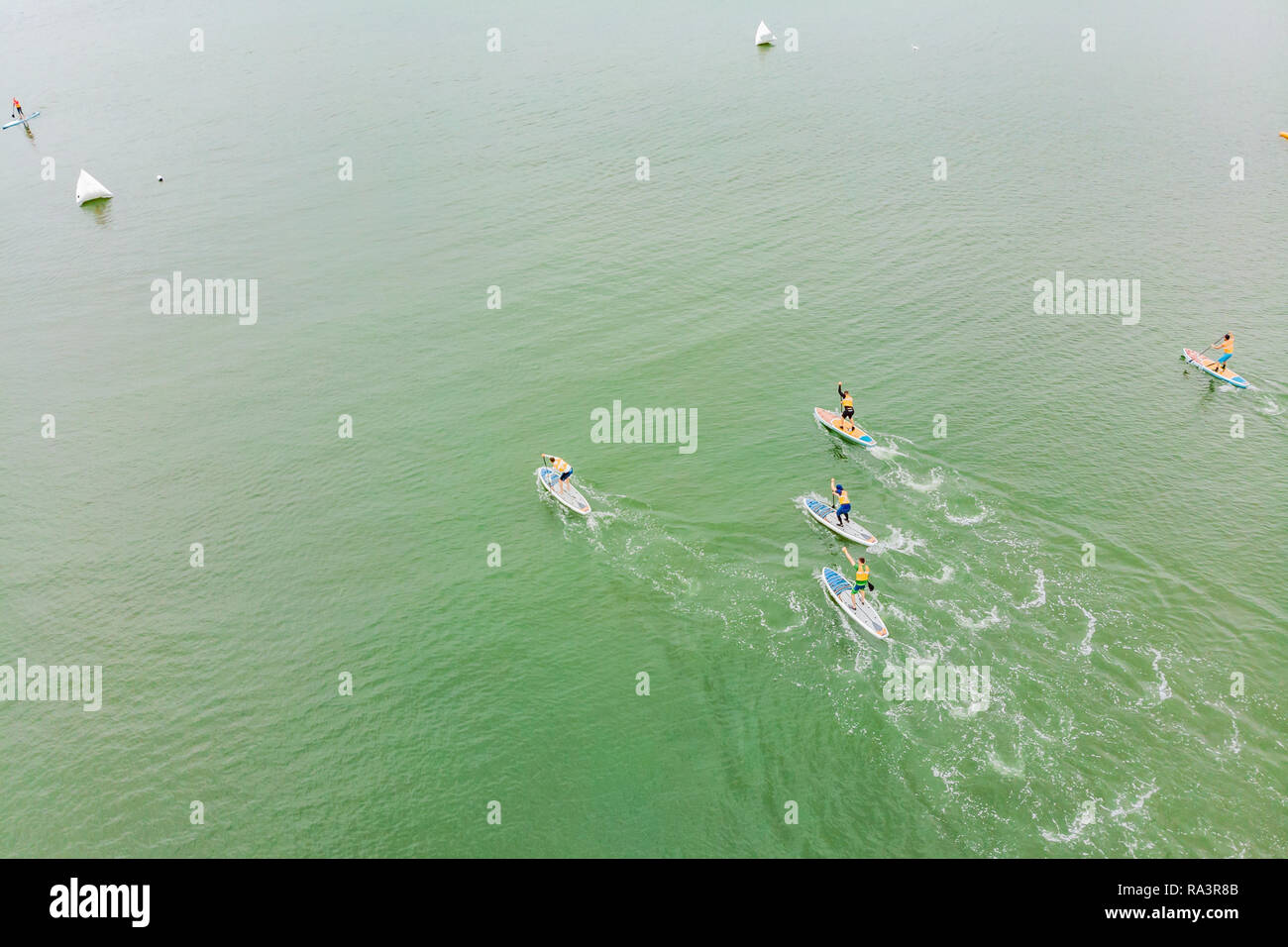 Uomini forti galleggiante su un SUP Board in una bellissima baia in una giornata di sole. Vista aerea di uomini attraversa la baia con il paddleboard. Sport acquatici, competizioni Foto Stock