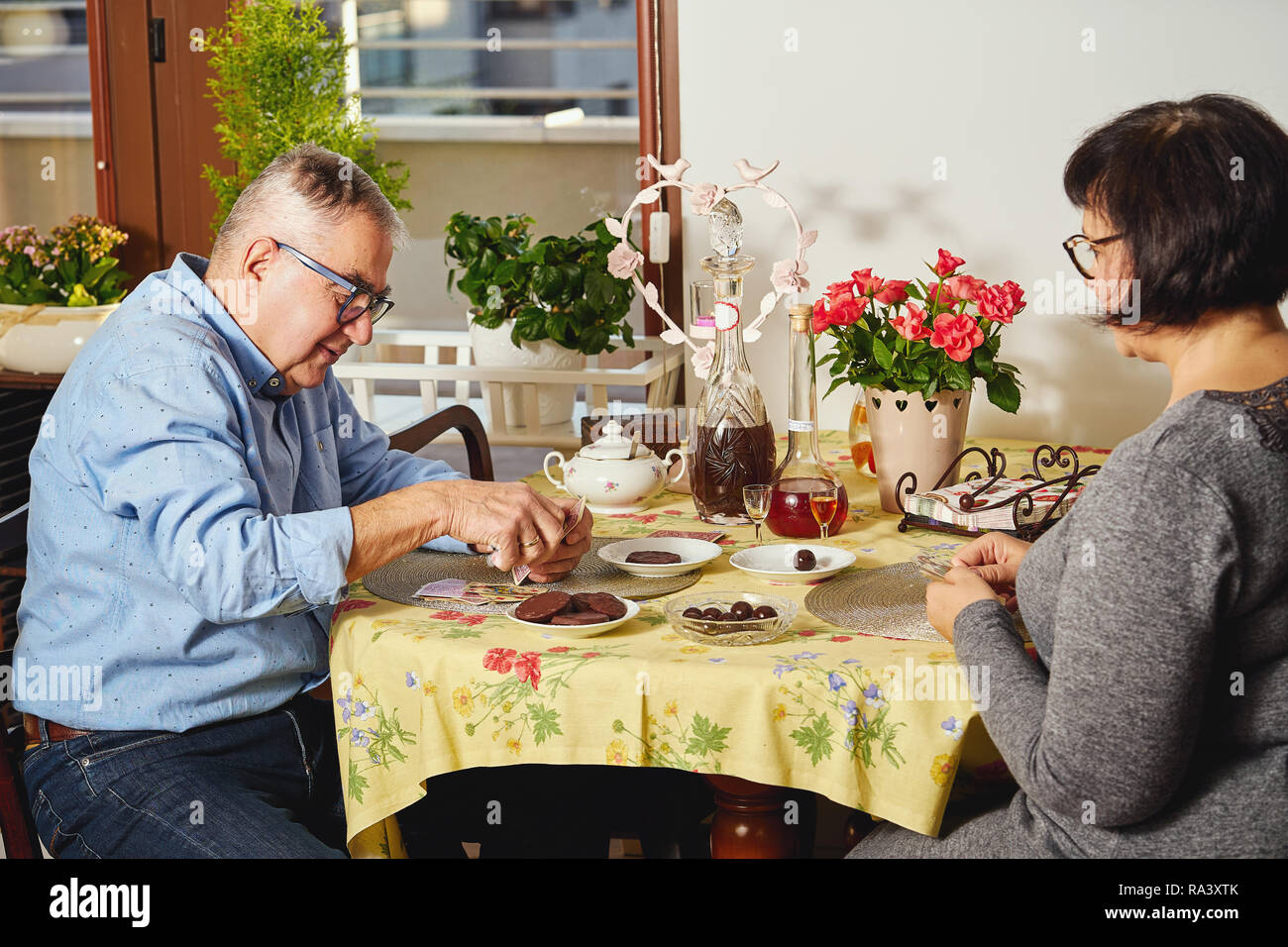 Felice gioiosa coppia senior giocando a carte o godendosi un snack a casa. Foto Stock