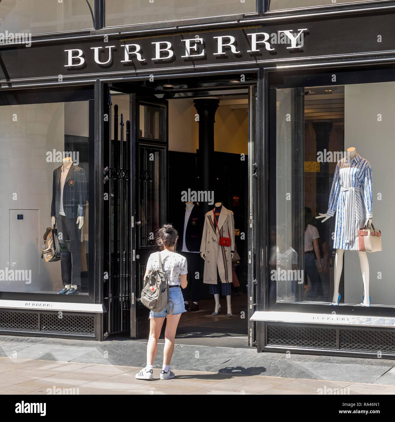La donna nella parte anteriore del negozio di abbigliamento Burberry, London, Regno Unito Foto Stock
