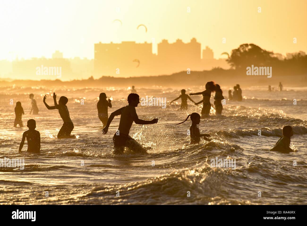 Molte persone la balneazione sulla spiaggia al tramonto, spiaggia Rambla, Montevideo, Uruguay Foto Stock