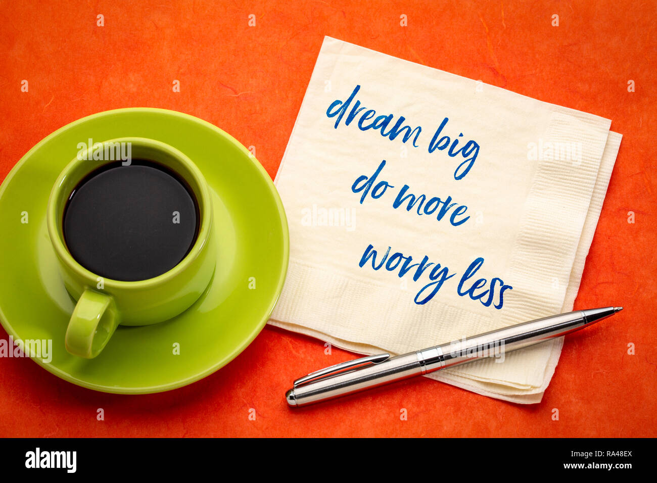 Grande sogno, fare di più, meno problemi - grafia di ispirazione su un tovagliolo con una tazza di caffè Foto Stock