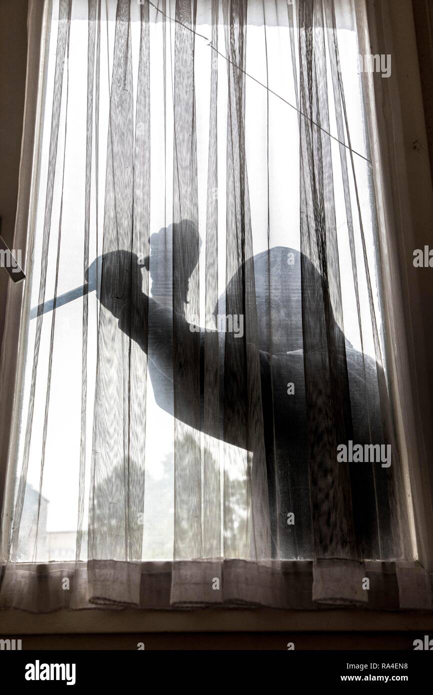 Immagine simbolo appartamento antifurto, autore tenta di rompere in un appartamento, preleva una finestra con un utensile Foto Stock