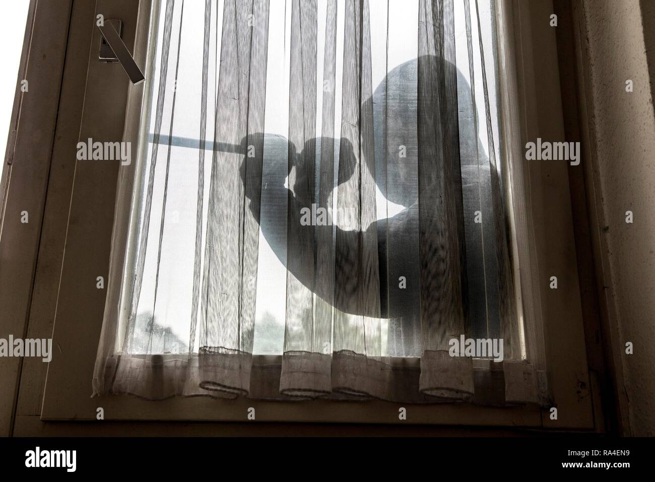 Immagine simbolo appartamento antifurto, autore tenta di rompere in un appartamento, preleva una finestra con un utensile Foto Stock