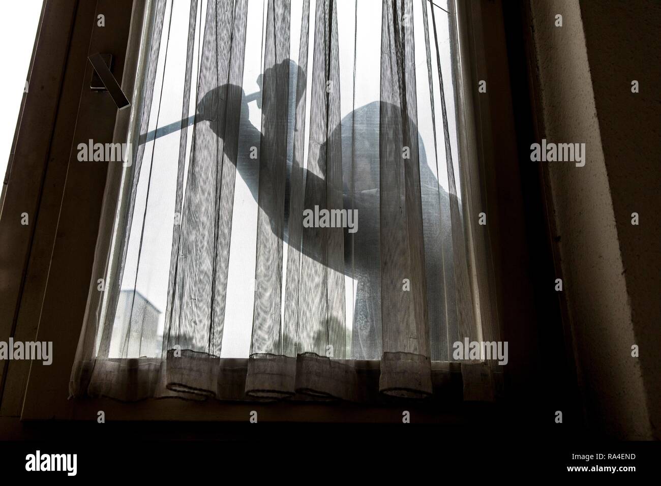 Immagine simbolo appartamento antifurto, autore tenta di rompere in un appartamento, preleva una finestra con un utensile Foto Stock