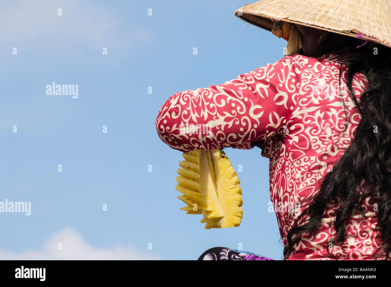 Una donna vietnamita azienda tagliare ananas frutta a vendere nel mercato galleggiante sul Fiume Hau. Can Tho, Delta del Mekong, Vietnam Asia Foto Stock