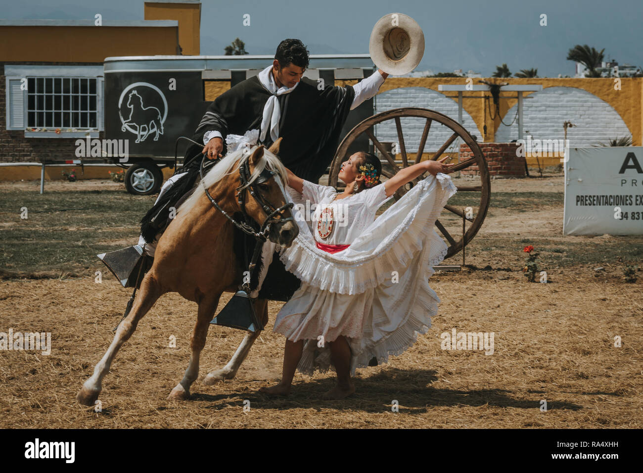 TRUJILLO, Perú - Settembre 2018 : Donna Peruviana in bianco tradizionale vestito carnevale ballando con cowboy a cavallo durante prestazioni all'aperto Foto Stock