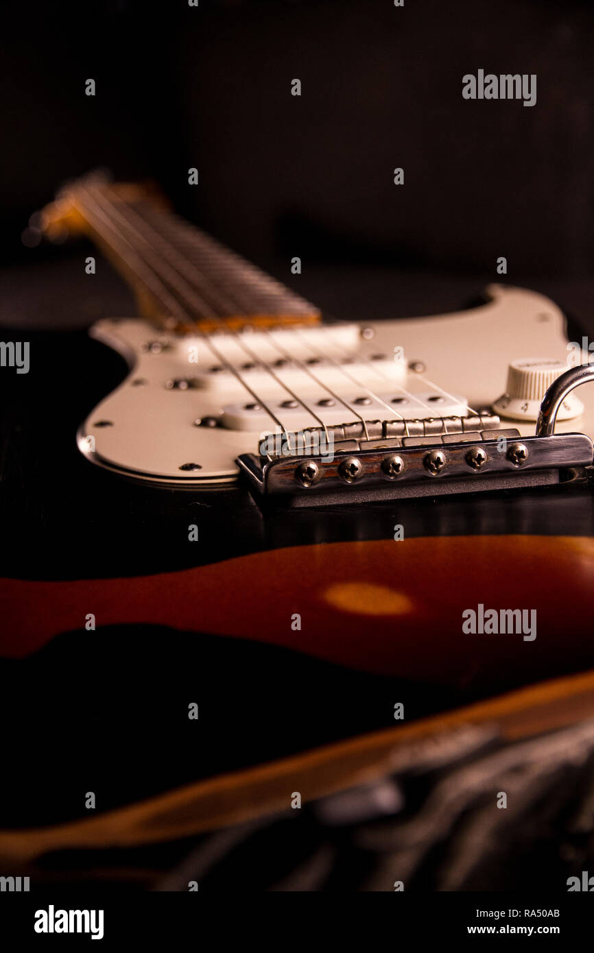 Close-up di uno squarcio colorato di chitarra elettrica coperto con vernice nera rimosso in corrispondenza di determinati punti per creare la usurata effetto Foto Stock