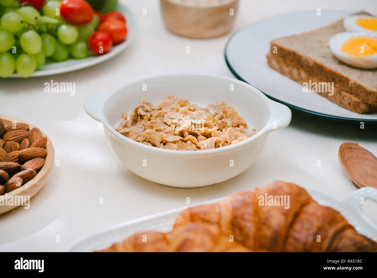 Luce sana colazione con i fiocchi d'avena. Hercules, noci, frutta, uova sode, pane. Oggetti per il servizio da tavola. Cibo sano. Foto Stock