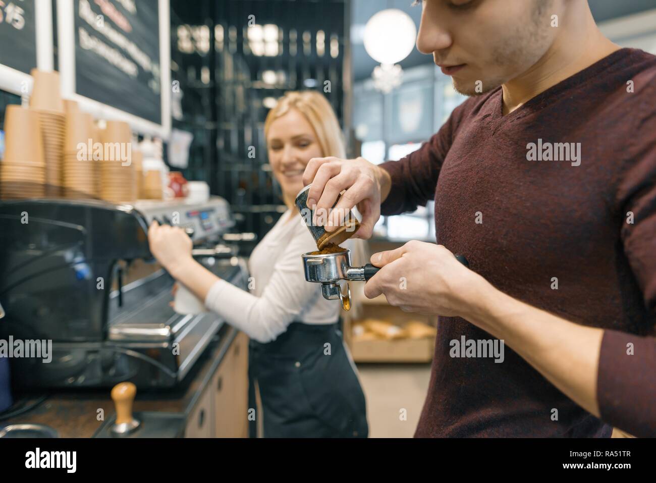 Barista uomo e donna fare il caffè, coppia di giovani che lavorano nella caffetteria. Foto Stock