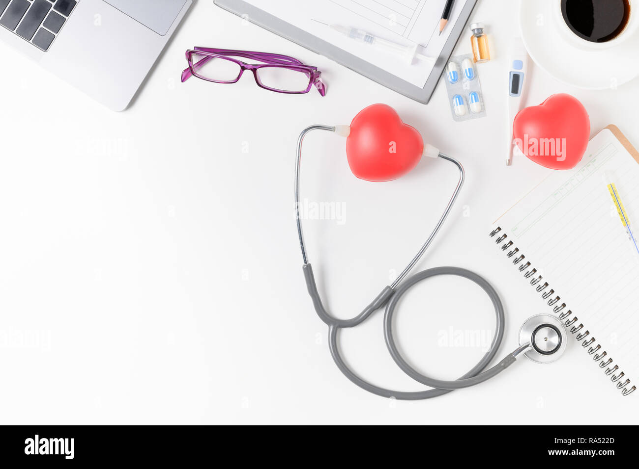 Vista superiore del medico scrivania con uno stetoscopio e cuore rosso, caffè e laptop. Vista da sopra con copia spazio, laici piana. Foto Stock