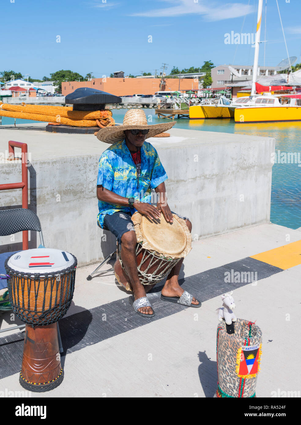 Maschio locale nel porto di San Giovanni Antigua giocando i tamburi di bongo per turisti Foto Stock