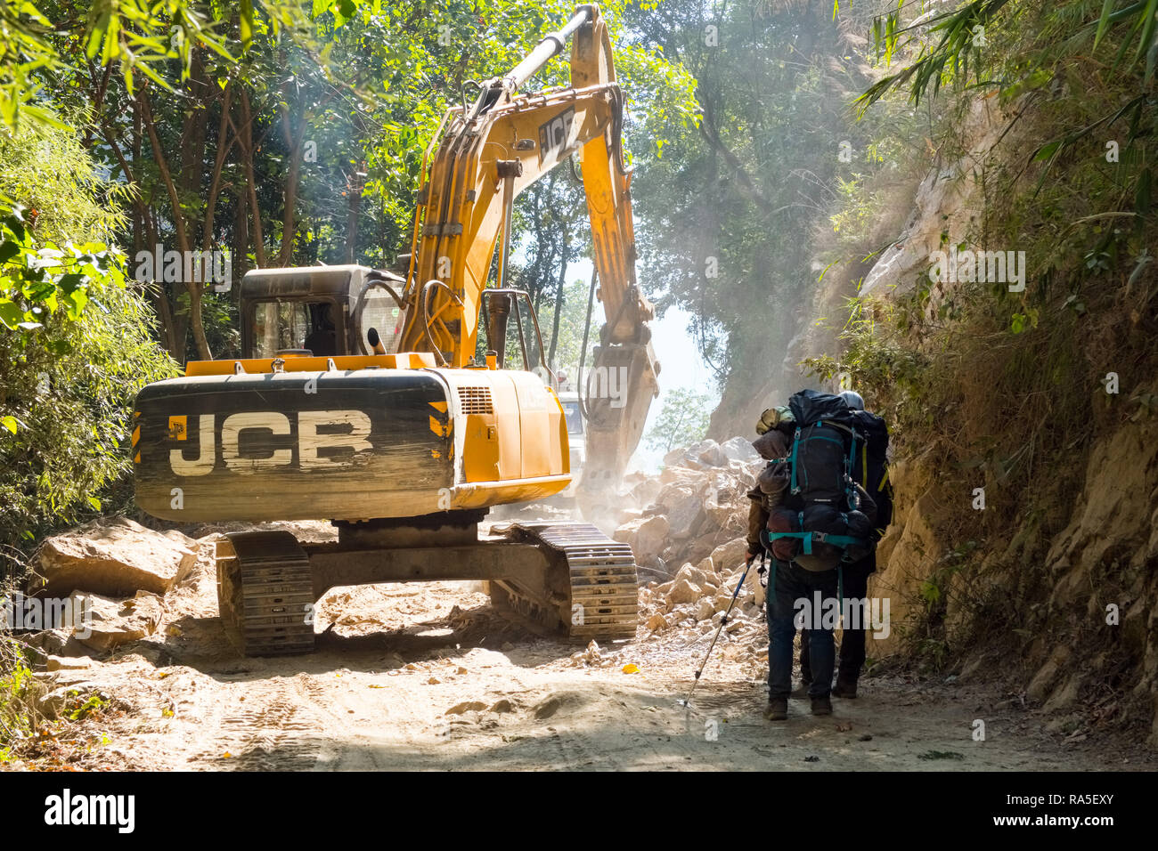 Trekking in attesa di passare un escavatore JCB alla costruzione di una nuova strada in Nepal Himalaya Foto Stock