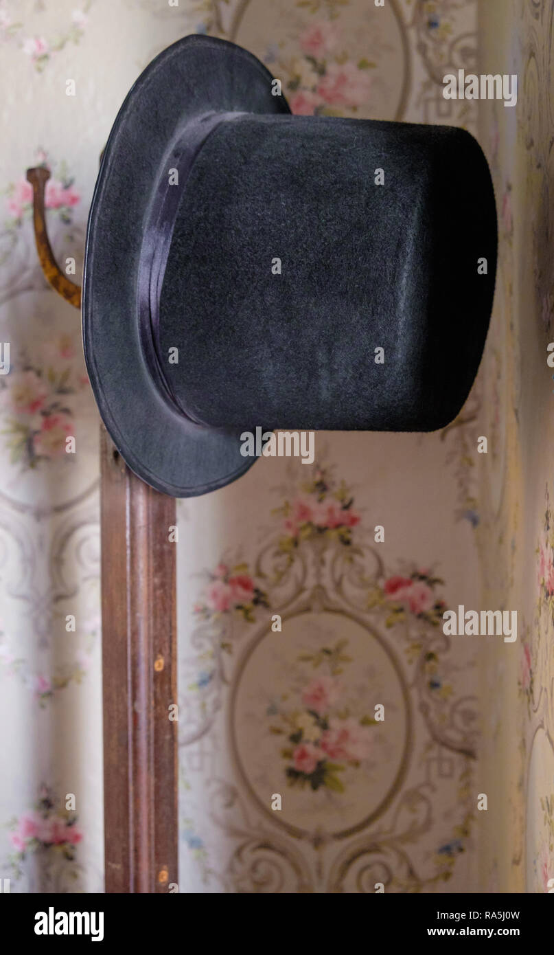 Annata nera top hat sul hat stand. Floreale carta da parati retrò in background. Interno della vecchia casa texano, Castagno Square McKinney Texas. Foto Stock