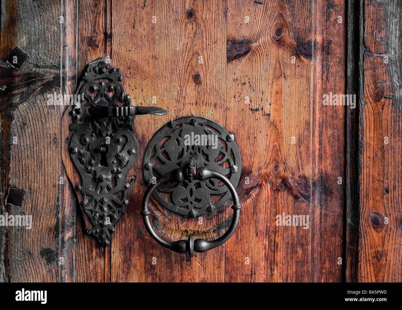 Forgiato la maniglia della porta e respingente su una vecchia porta di legno, Austria Foto Stock