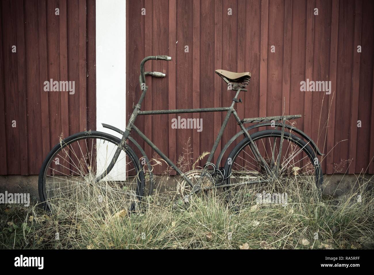 Vecchia bicicletta si appoggia contro una rossa svedese casa in legno, Värmland, Svezia Foto Stock