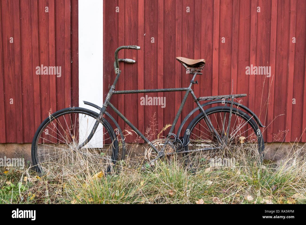 Vecchia bicicletta si appoggia contro una rossa svedese casa in legno, Värmland, Svezia Foto Stock