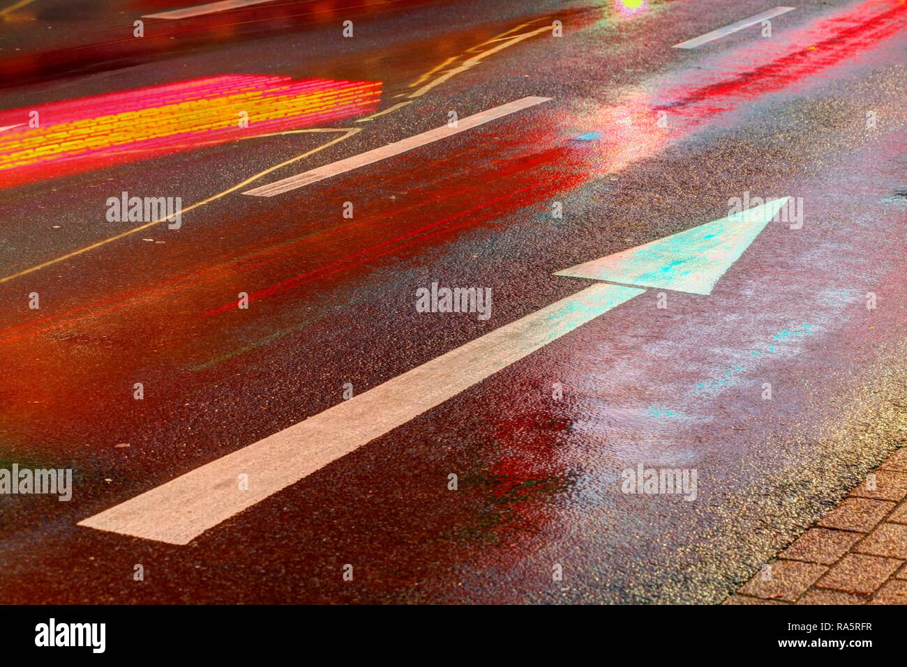 Strada bagnata, luci della freccia di direzione sotto la pioggia al tramonto, Brema, Germania Foto Stock