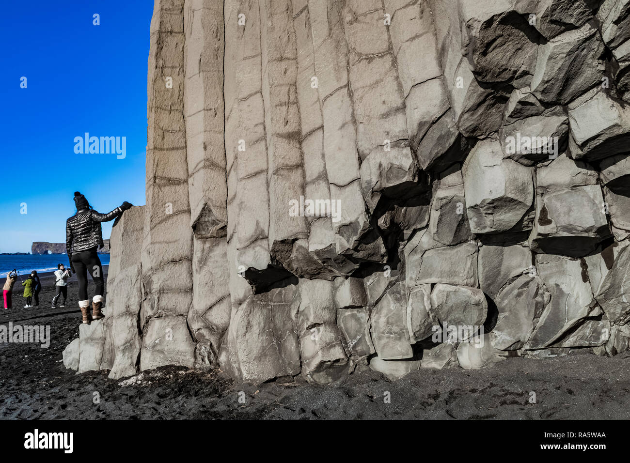 Turisti che si godono il basalto colonnare formazioni Reynisfjara lungo la spiaggia di sabbia nera in Islanda [Nessun modello di versioni disponibili per le licenze editoriali o Foto Stock