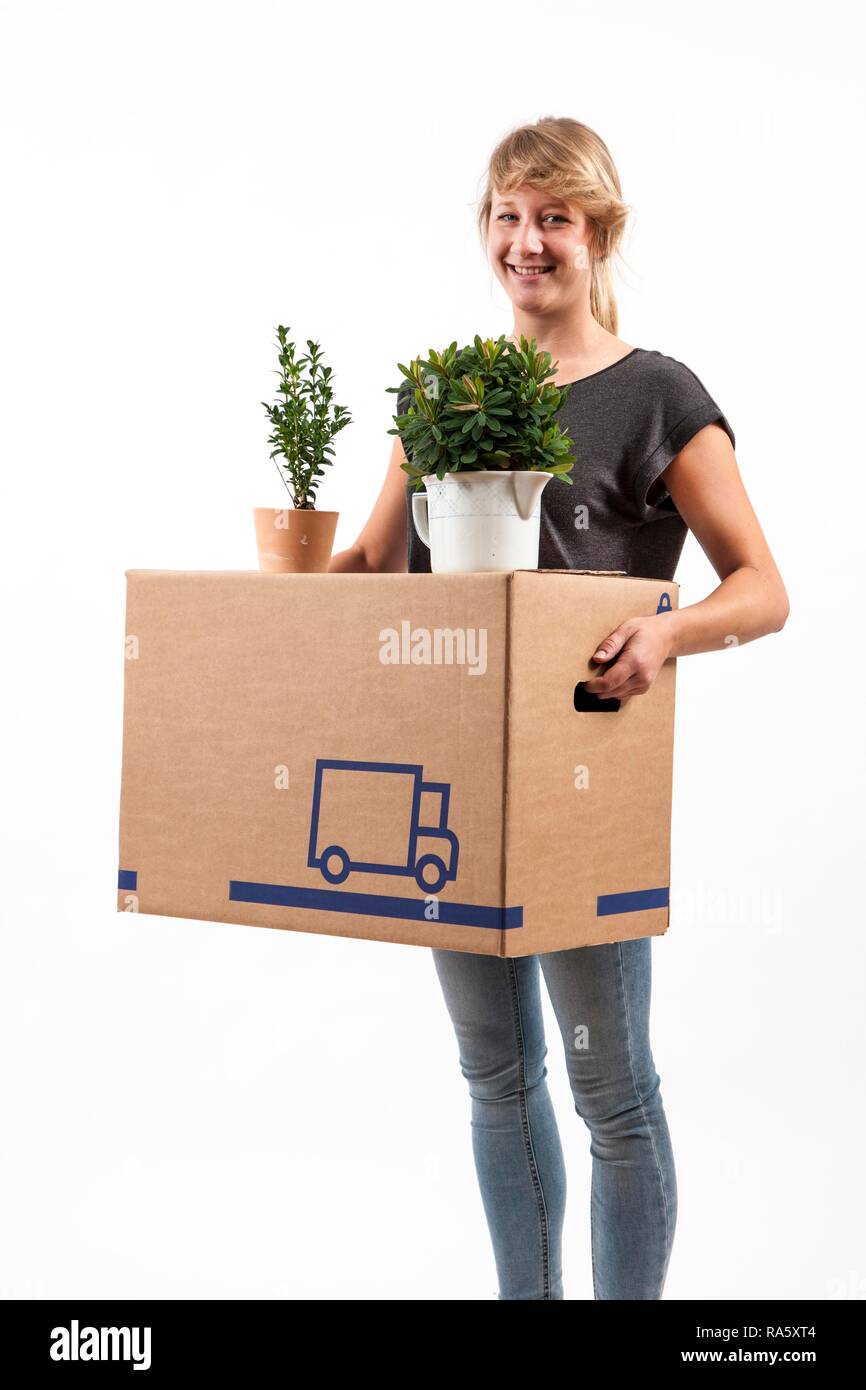 Giovane donna che porta una scatola di movimentazione e piante di casa Foto Stock