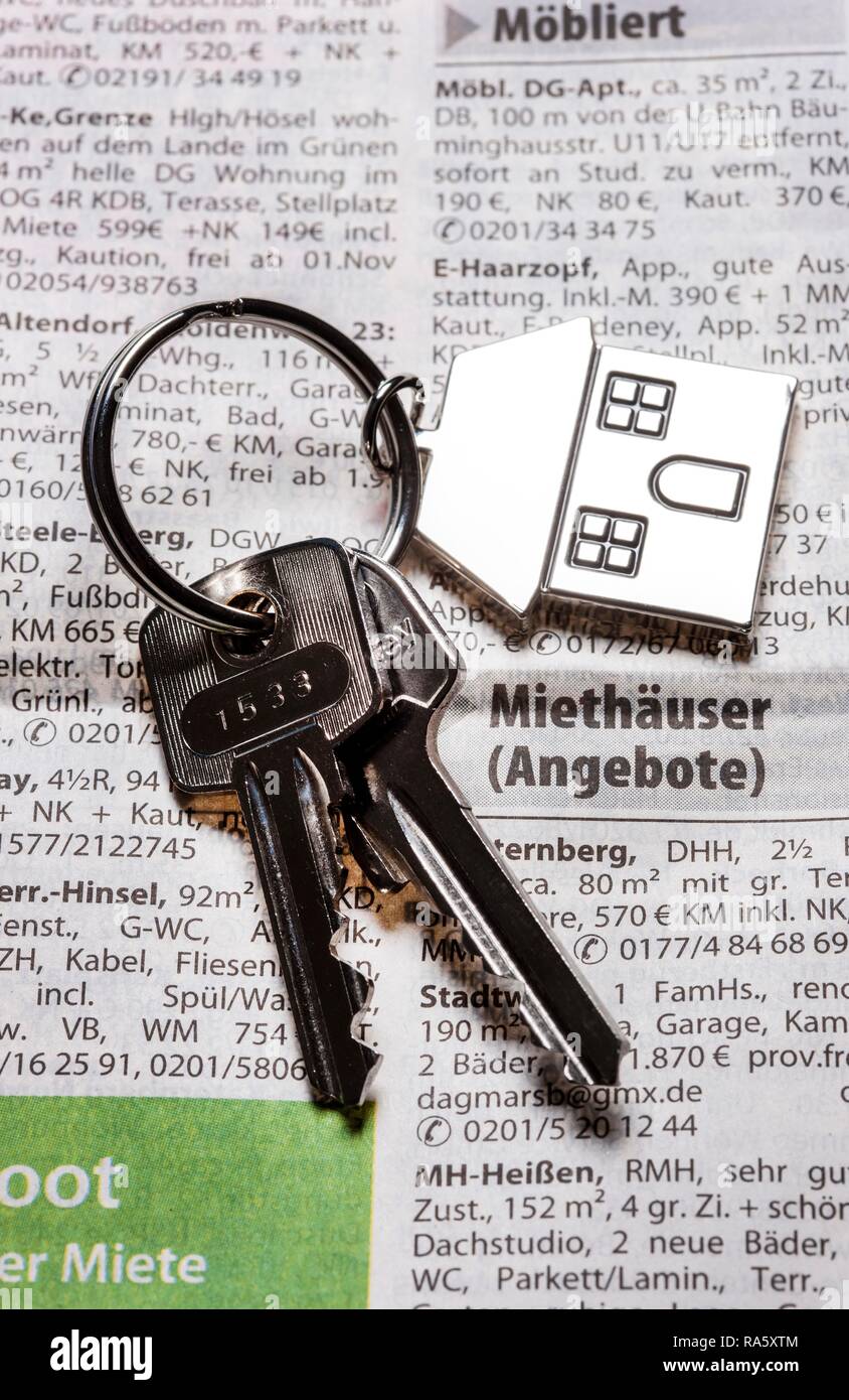 Due chiavi con una chiave in metallo a forma di etichetta come una casa che giace sul patrimonio immobiliare di pagina di un quotidiano, immagine simbolica per la casa Foto Stock