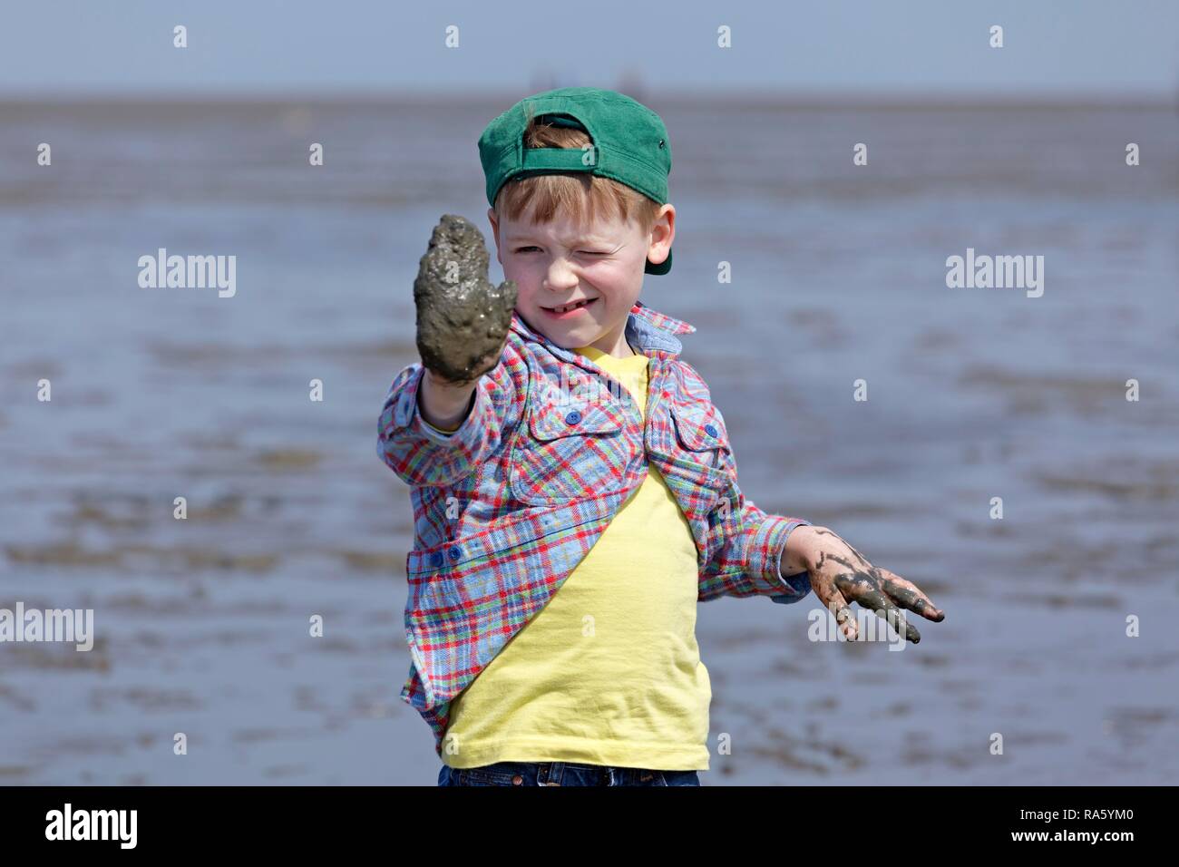 Ragazzo con le mani piene di fango delle velme del mare di Wadden, Duhnen, Cuxhaven, Bassa Sassonia, Germania Foto Stock