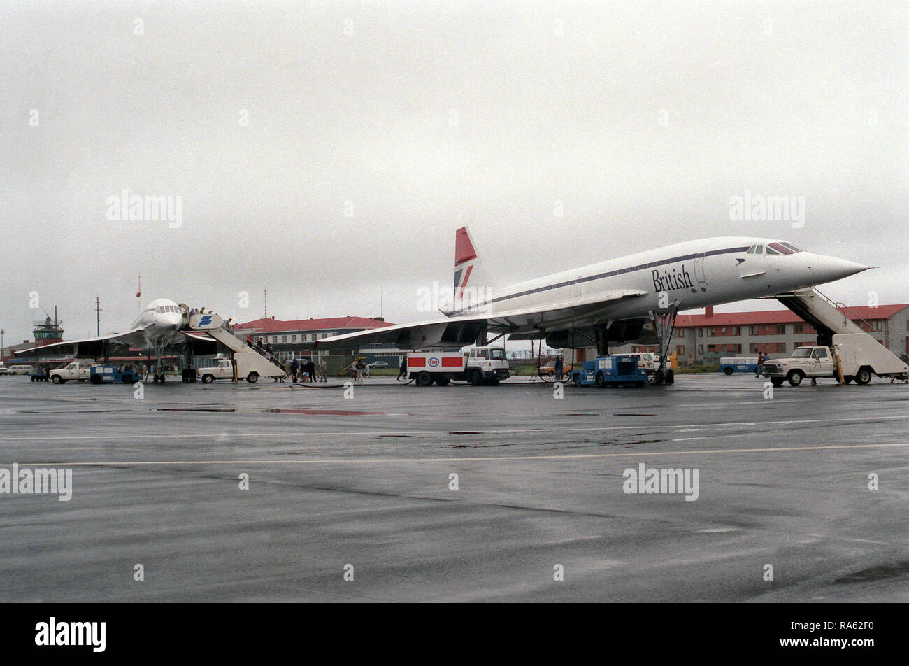 1977 - Una vista anteriore destra di due British Airways Concorde aeromobili parcheggiati sulla linea di volo. Gli aerei sono su un intorno al mondo per la prova di volo. Foto Stock