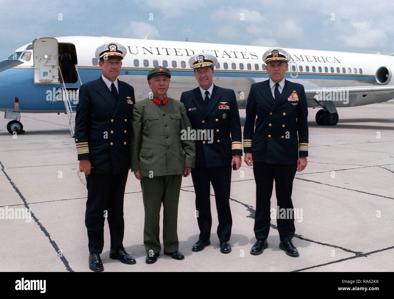 1980 - un membro di una delegazione dalla Cina è fotografato con tre Navy bandiera ufficiali. Vice Presidente Walter Mondale del velivolo ufficiale è in background. Foto Stock