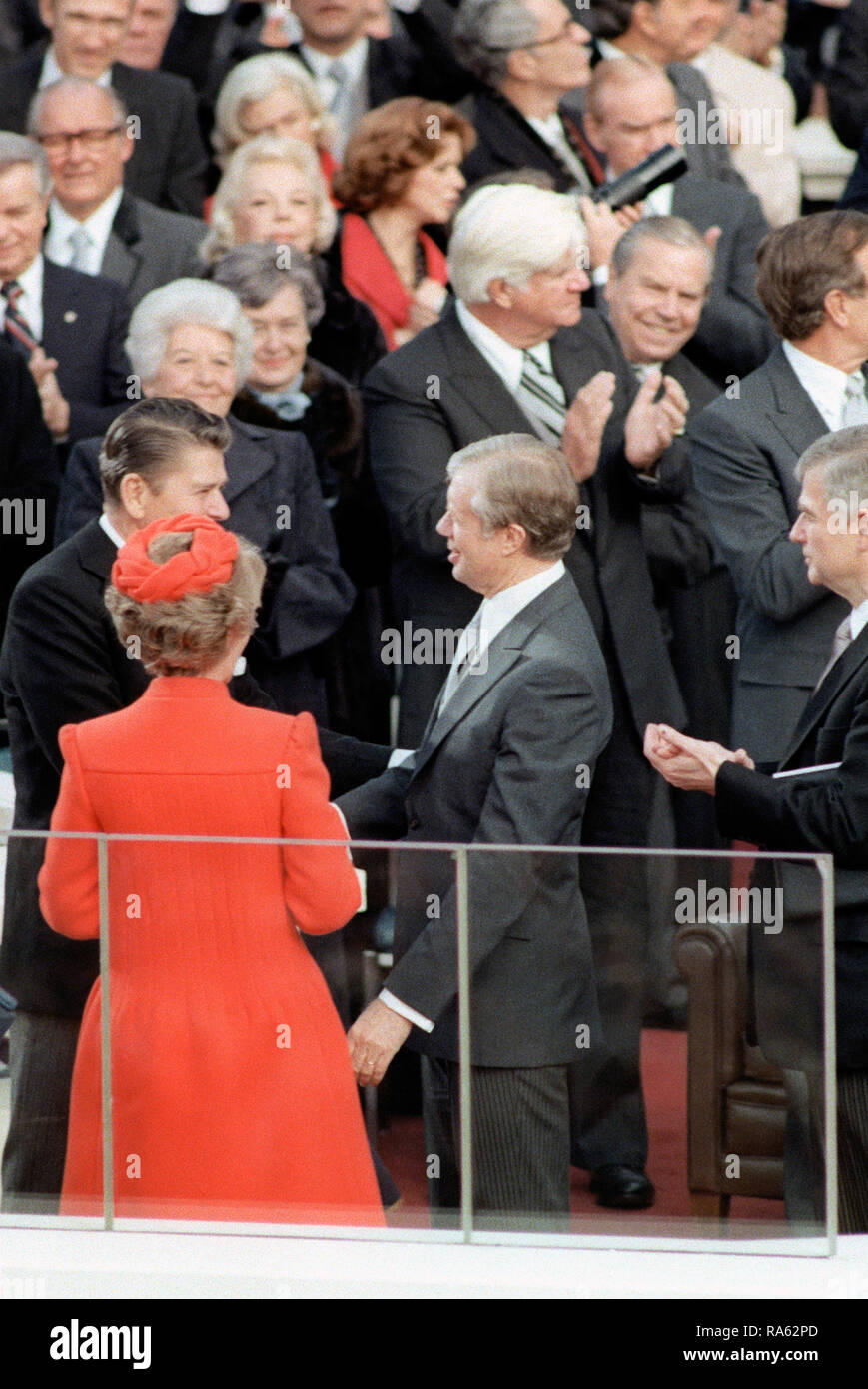 1981 - Presidente uscente Jimmy Carter si congratula con Ronald Reagan, il nuovo presidente, al Campidoglio durante il giorno dell'inaugurazione. Nancy Reagan si osserva la scena. Foto Stock