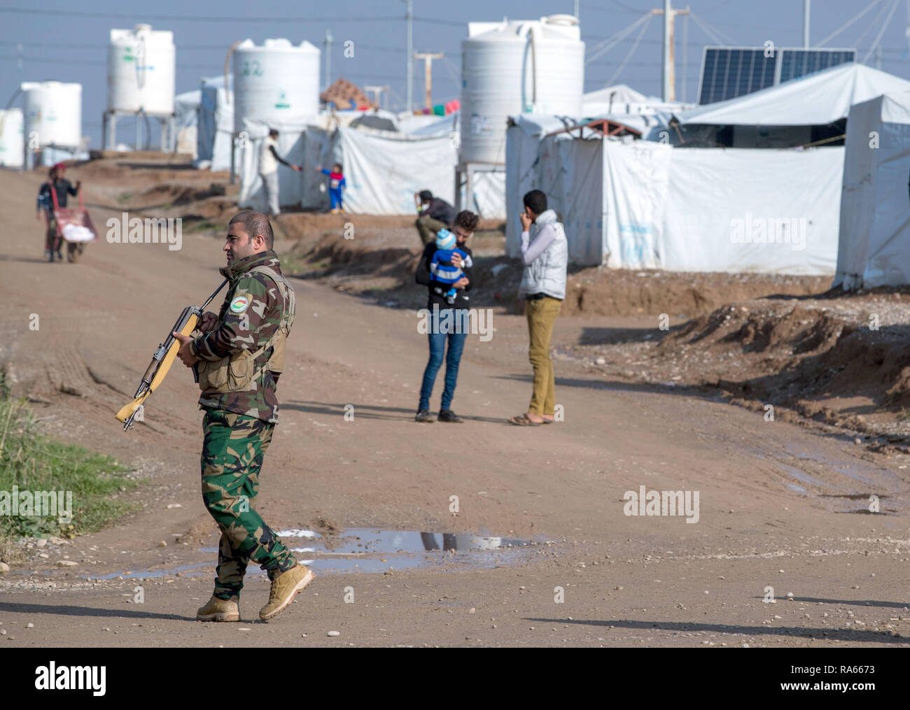 19 dicembre 2018, l'Iraq, Hasan Sham: Un dipendente armati interni dei servizi segreti della regione autonoma del Kurdistan, Asayî· (Asayesch) è nelle persone internamente sfollate camp Hasan Sham. Il servizio segreto è stata fondata nel settembre 1993 ed è utilizzato principalmente per la lotta contro il terrorismo. Hasan Sham tenda del campo vicino alla gran parte distrutta ex roccaforte è di Mossul ospita 3.300 dei 1,8 milioni di sfollati interni in Iraq. Foto: Jens Büttner/dpa-Zentralbild/ZB Foto Stock