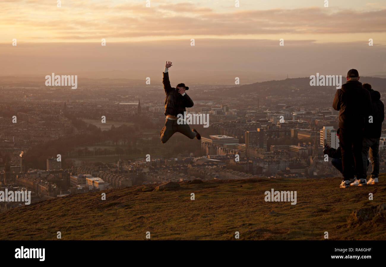 Edimburgo, Scozia, Regno Unito. Il 2 gennaio 2019. Regno Unito meteo, il turista a godere la vista da Arthur sede del vertice di Holyrood Park appena intorno al tramonto, sebbene la temperatura è meno 1 grado dopo una notte di meno di sei gradi. Foto Stock