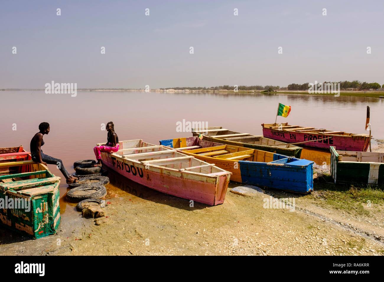 Due giovani donne seduti sulle colorate barche di legno a Lac Rose, regione di Dakar, Senegal Foto Stock